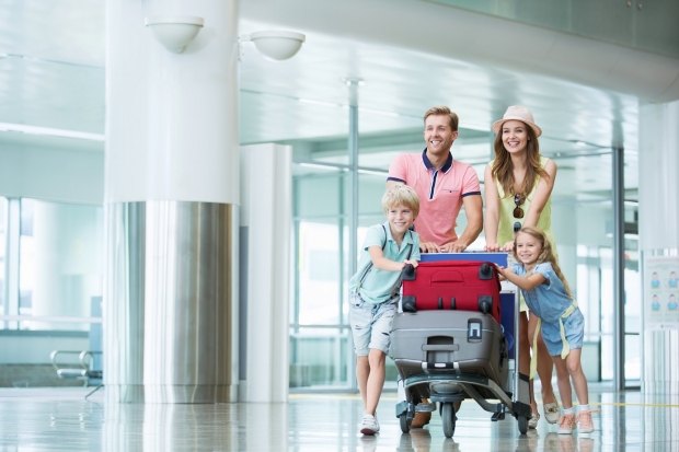 famille dans un hall d'aeroport qui pousse un chariot de bagages