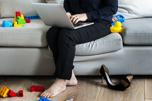 woman working on a laptop with toys on the ground
