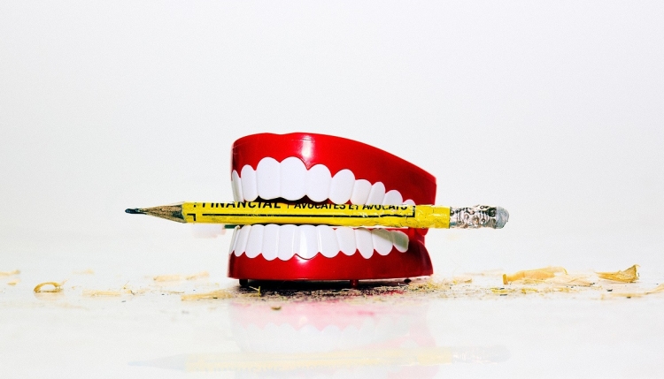 Dentiers avec un crayon jaune entre les dents